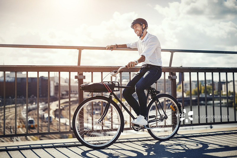 快乐的商人在城市的桥上骑着自行车图片素材