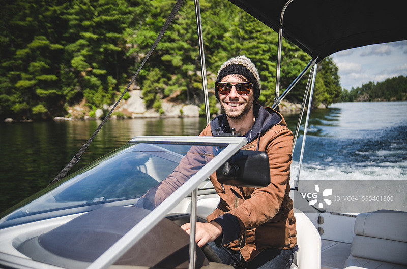 微笑的年轻成年男子在湖上驾驶摩托艇羊毛帽子图片素材