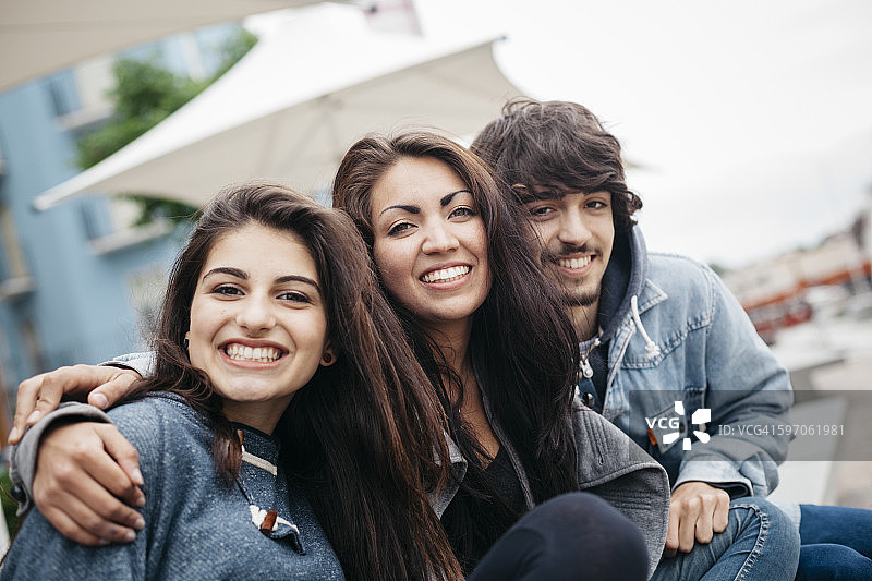 意大利，里米尼，三个快乐的朋友在户外拥抱的肖像图片素材