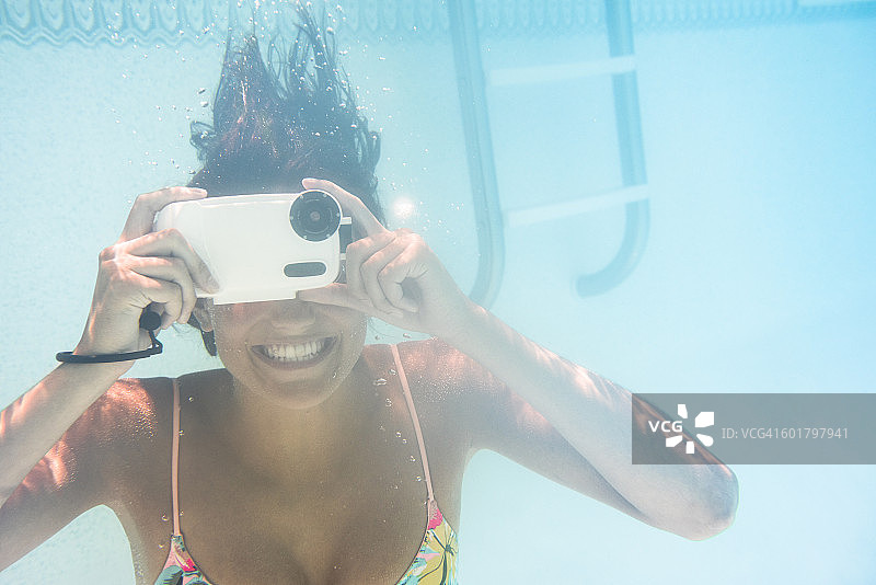一个白人女人在游泳池里使用水下摄像机图片素材