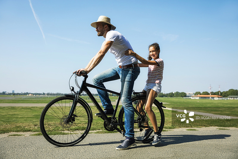 快乐的男人和女儿骑自行车图片素材