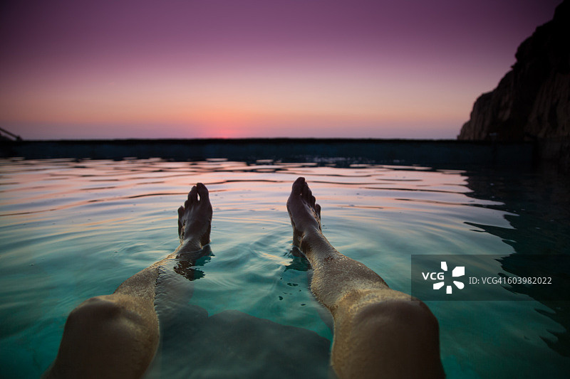 从个人角度来看，在地中海科斯塔布拉瓦海岸线的一个天然游泳池里游泳，看着日出，他的脚在夏天的时候漂浮在水里。图片素材