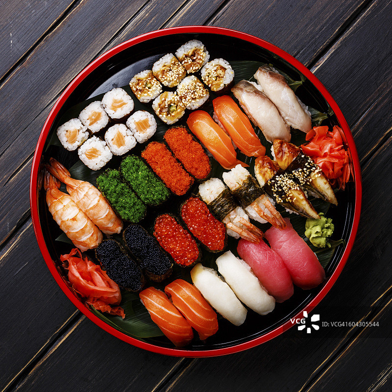寿司集棒看，手握寿司和卷在传统的日本黑色寿司圆盘图片素材