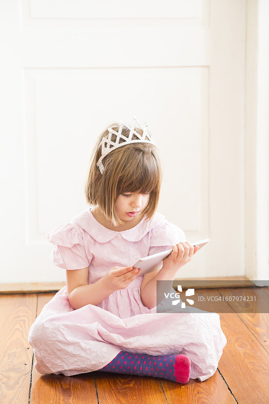 小女孩打扮成公主看着平板电脑图片素材