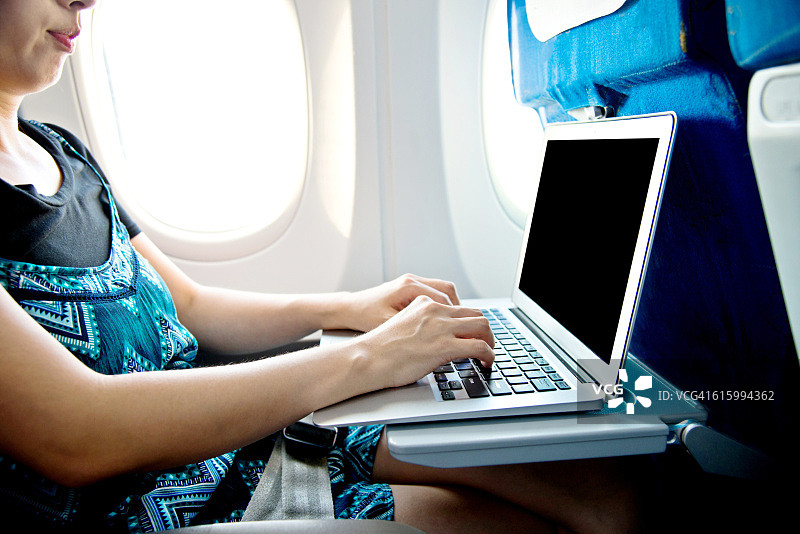 在飞机上使用笔记本电脑的女人图片素材