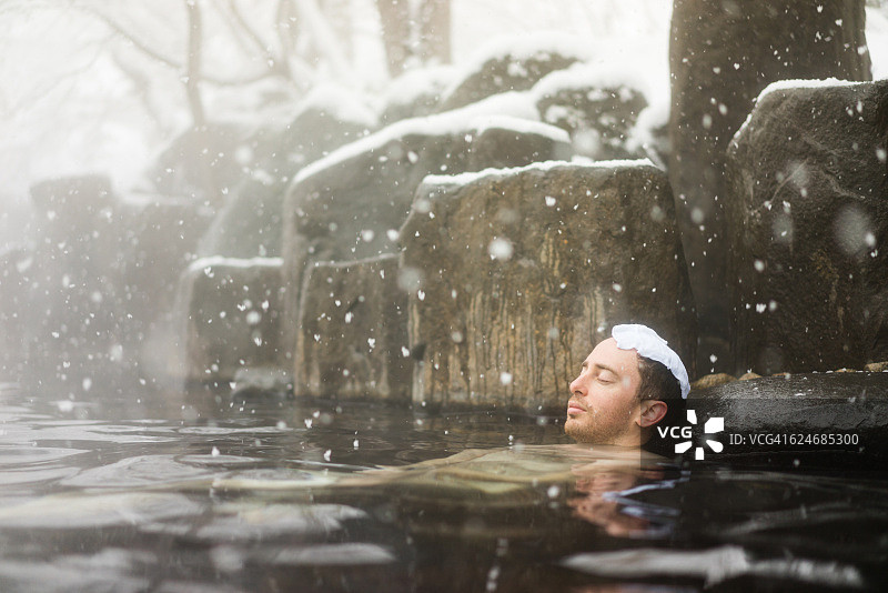 西方游客在冬雪中享受天然温泉图片素材