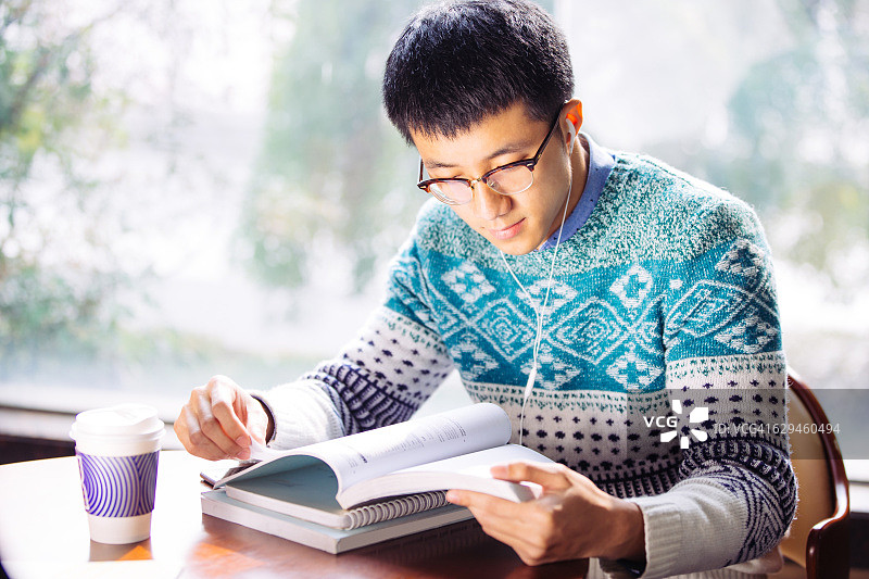 年轻的亚洲男子学生在图书馆看书图片素材