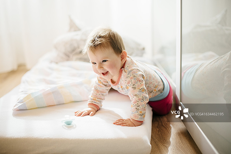 微笑的小女孩在床垫上爬的肖像图片素材