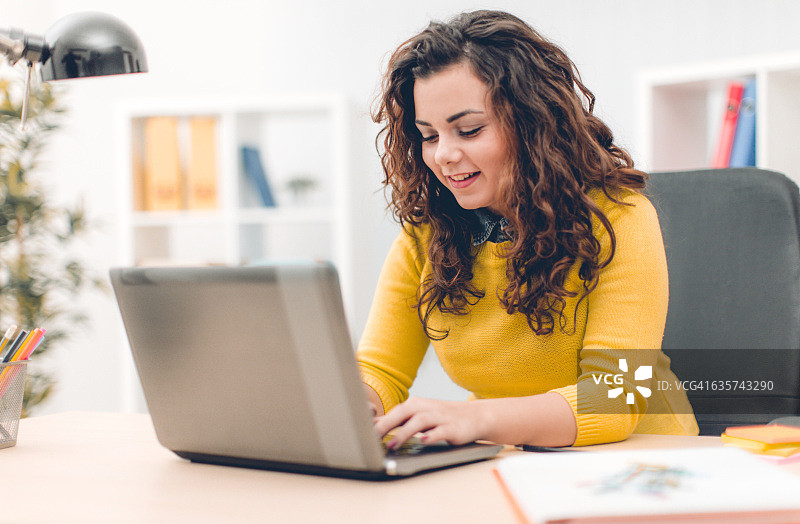 商务女性在现代办公室使用笔记本电脑图片素材