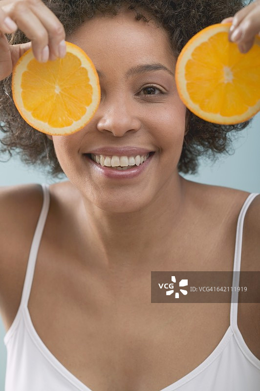 一个年轻女子拿着橘子片挡在面前图片素材