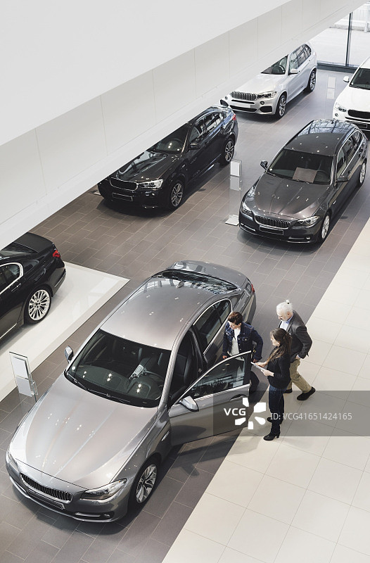 高视角的销售人员向客户解释在汽车展厅图片素材