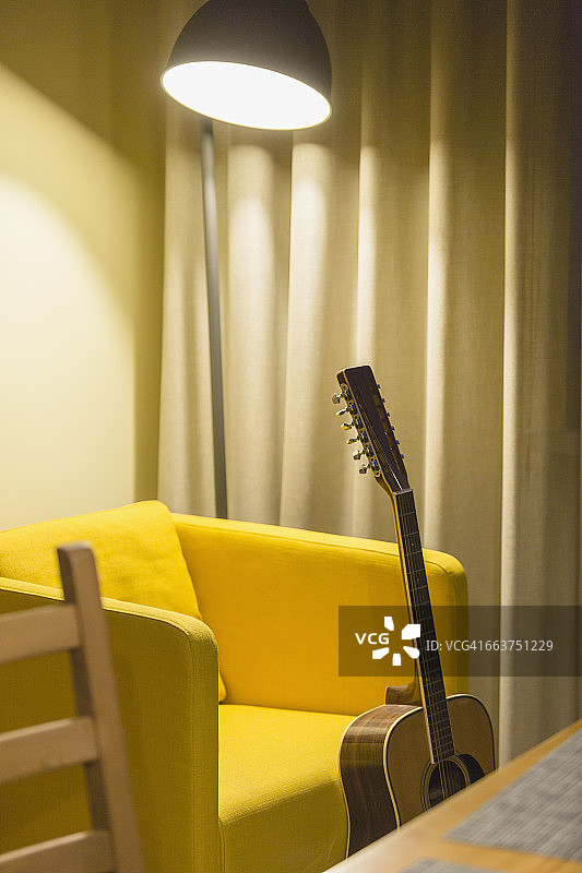 在家里用吉他对抗黄色的椅子图片素材