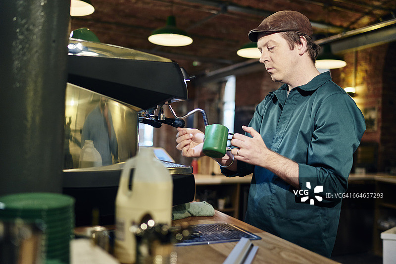 男咖啡师在咖啡店的咖啡机上加热牛奶壶图片素材