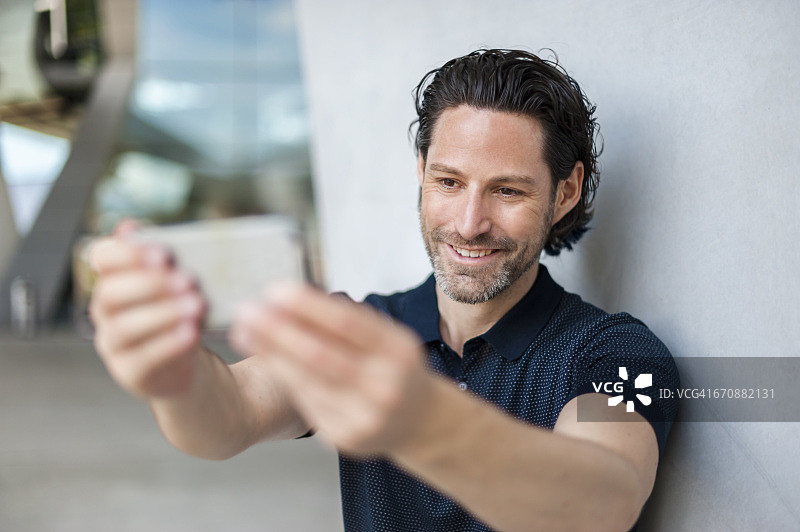 微笑的男人用手机自拍的肖像图片素材