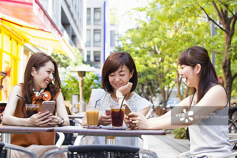 商业女性在户外咖啡馆操作智能手机图片素材