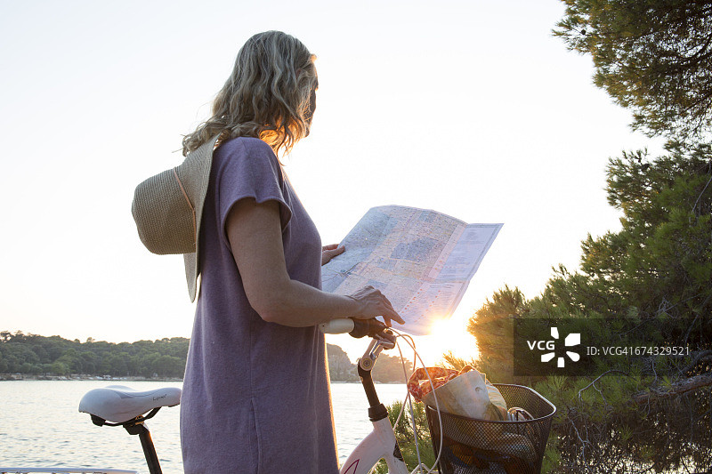 一个女人在海上看自行车旅行地图图片素材