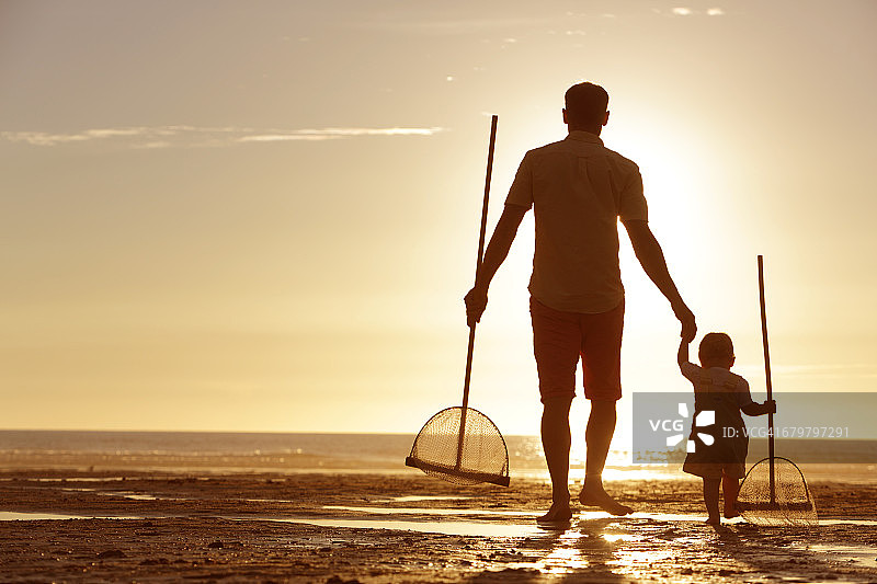 日落时分，父亲和女儿在海滩上散步图片素材