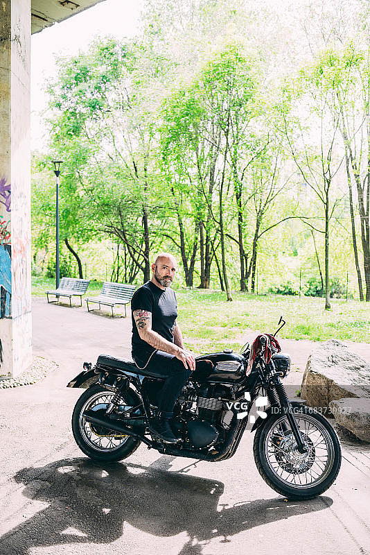成熟的男性摩托车手坐在摩托车上的肖像图片素材