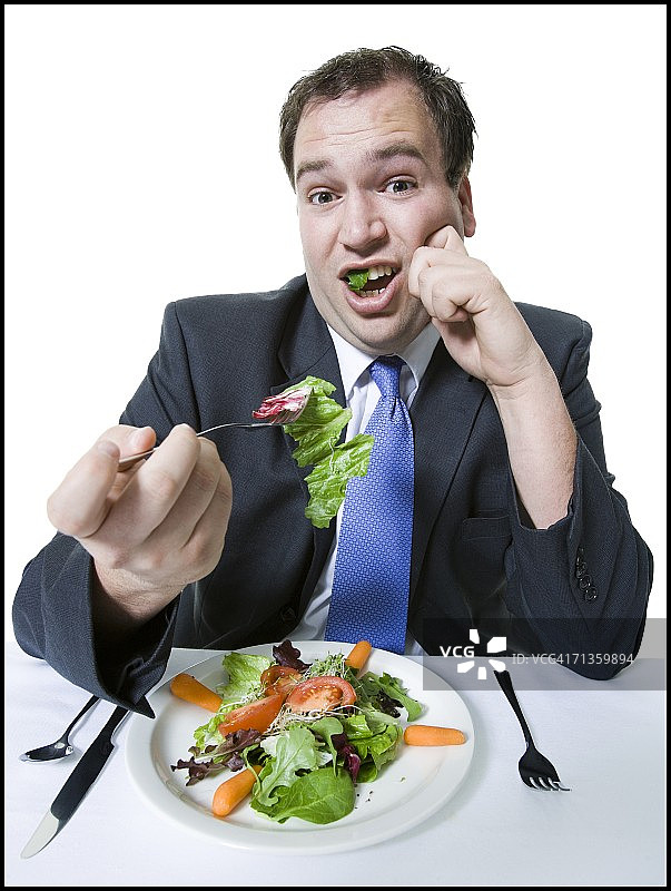 一个年轻人正在吃蔬菜沙拉图片素材