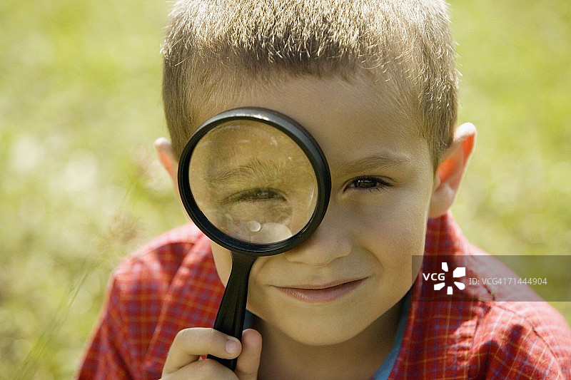 一个男孩用放大镜看的肖像图片素材