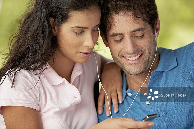 一个中年男人和一个年轻女人在听MP3的特写图片素材