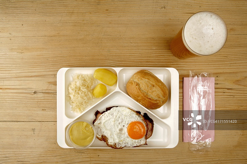盘子里放着鸡蛋、香肠、泡菜、土豆和面包，旁边放着一杯啤酒图片素材