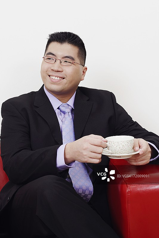 一个商人坐在沙发上与一杯茶和微笑的特写图片素材