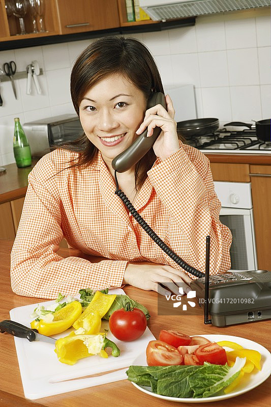一个年轻女人在厨房里打电话的肖像图片素材