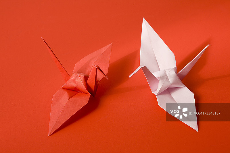 红色背景上的两只折纸鹤，特写图片素材
