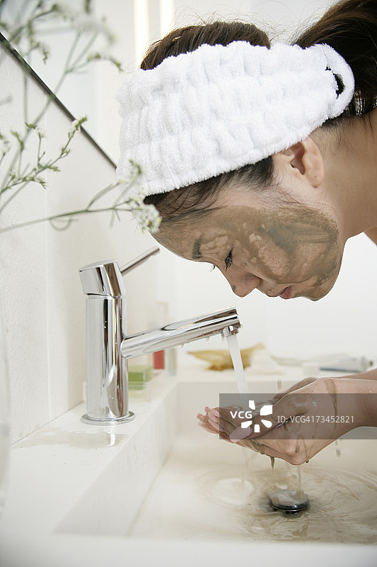 一个年轻的女人在盥洗室洗脸的特写图片素材