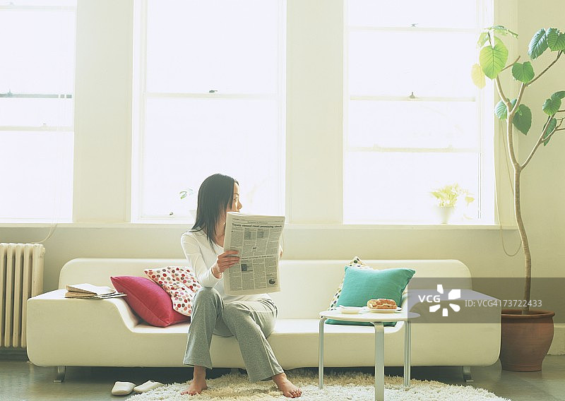 坐在沙发上看报纸的女人图片素材