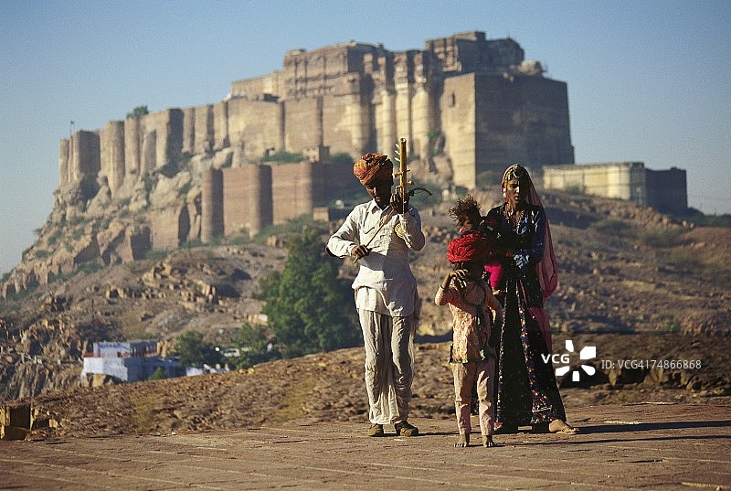 印度拉贾斯坦邦焦特布尔，一名正在弹奏乐器的中年男子，身边是他的妻子和孩子图片素材