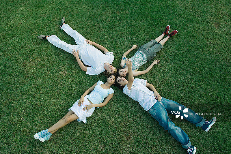 "一群年轻人躺在草地上，头朝下"图片素材