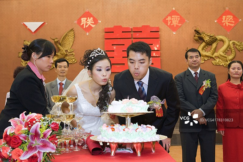 新婚夫妇一起吹灭结婚蛋糕上的蜡烛图片素材