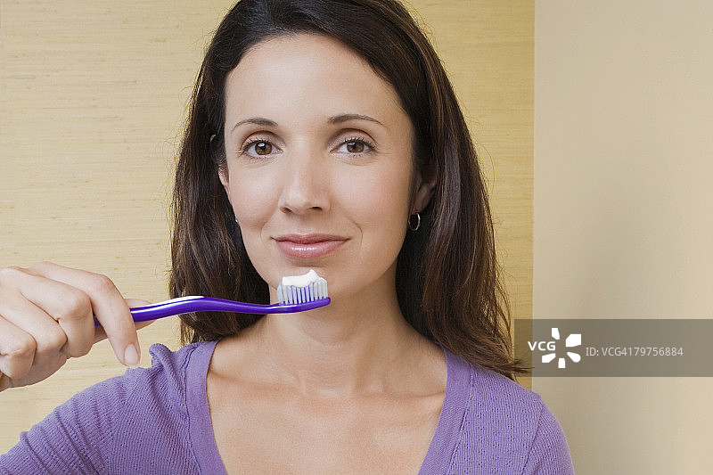 一个中年妇女的肖像拿着牙刷在她的嘴前面图片素材