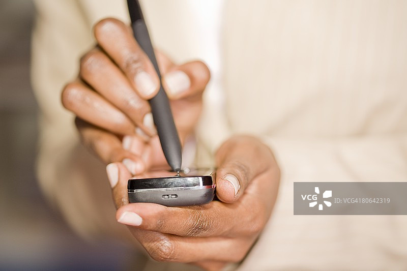 特写的黑人女商人用钢笔在手机上打字短信图片素材