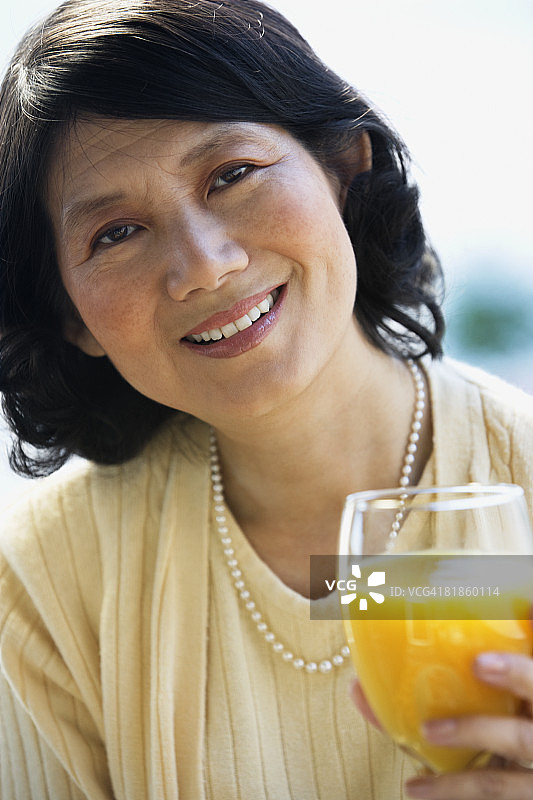 喝橙汁的亚洲女人图片素材
