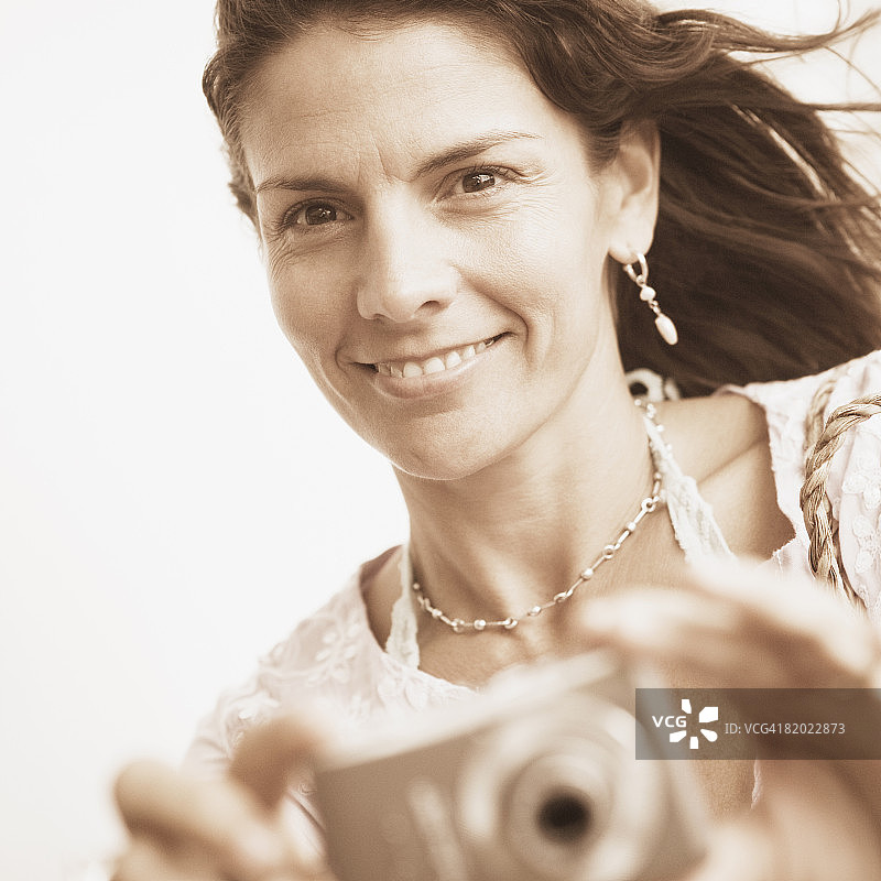 一个中年妇女用数码相机拍照的肖像图片素材