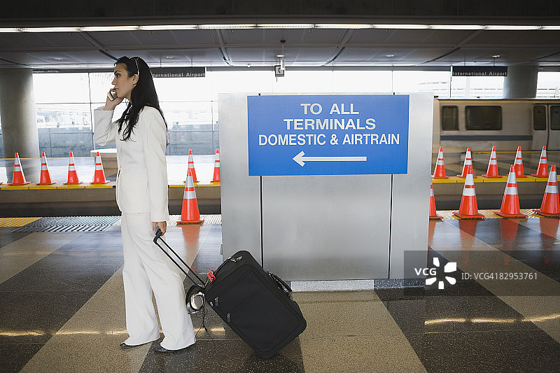 一个女商人在地铁站边打电话边拉行李的侧面图图片素材