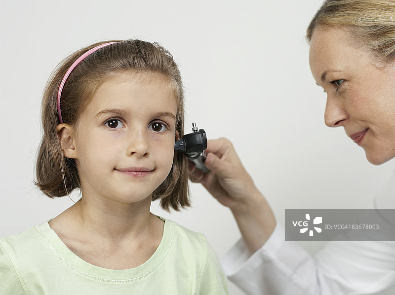 女儿科医生用耳镜检查女孩的耳朵图片素材