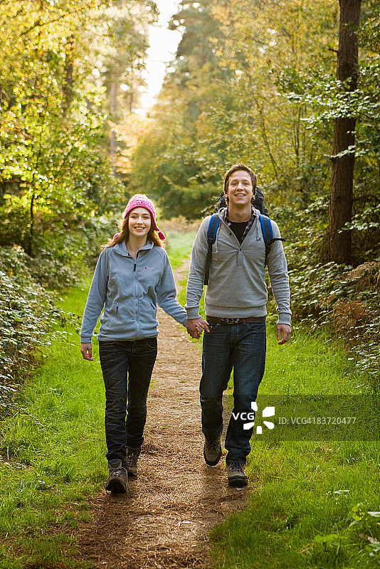 一对情侣在森林的小路上徒步旅行。图片素材