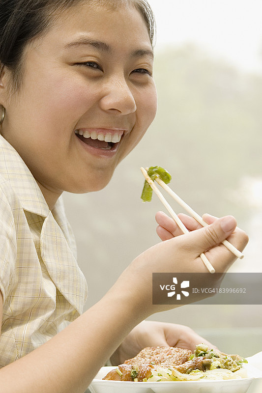 一个女办公室工作人员用筷子和微笑午餐的特写图片素材
