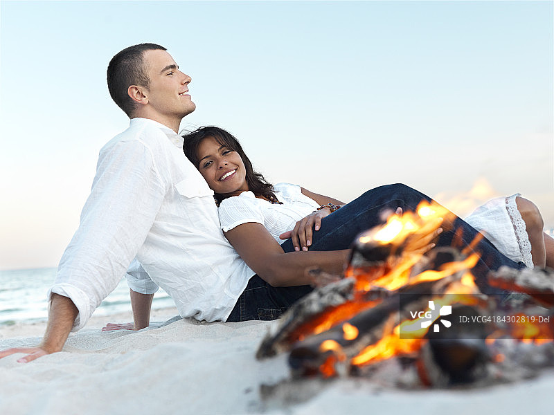 年轻夫妇在海滩上篝火旁放松图片素材