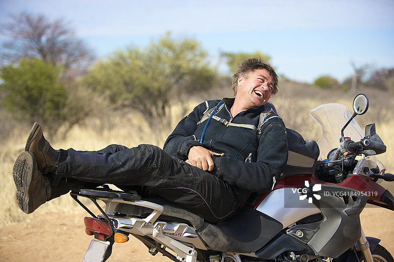 博茨瓦纳喀拉哈里沙漠中部，一名车手在他的车顶上休息图片素材