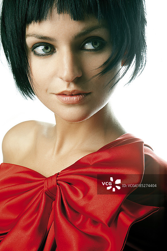黑头发穿着红色蝴蝶结礼服的年轻女子图片素材