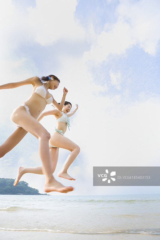 两个年轻女人在海滩上跑步图片素材