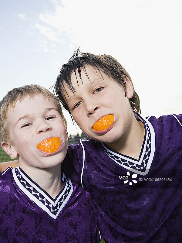 穿着足球制服的男孩的肖像，嘴里有橙色的楔子图片素材