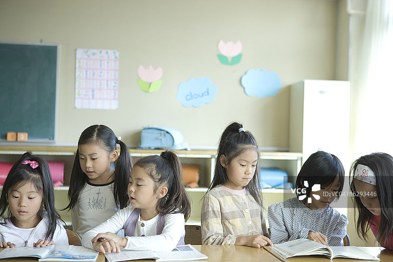 女学生(6-9岁)在教室里阅读课本图片素材