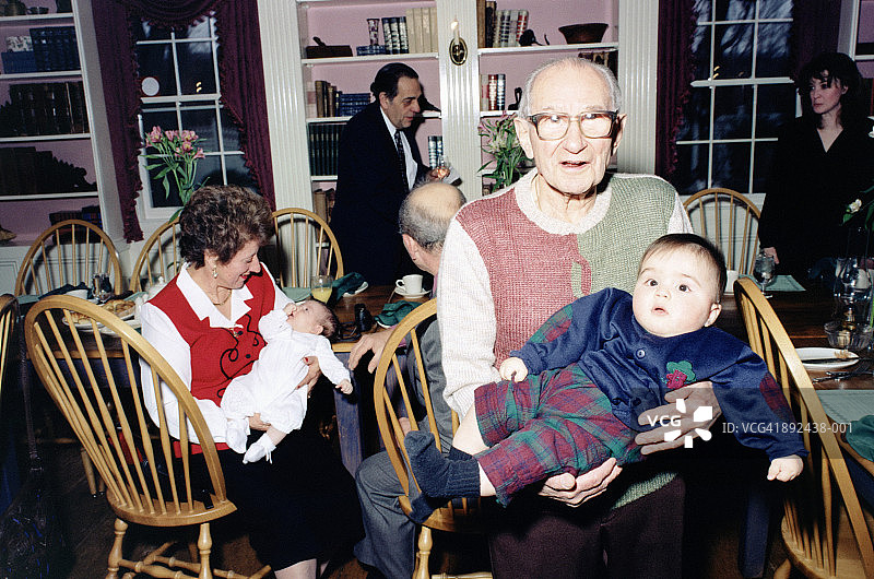 晚餐派对后，祖父母抱着婴儿(3-9个月)图片素材