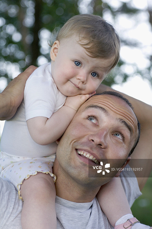 一个孩子坐在她父亲的肩上图片素材